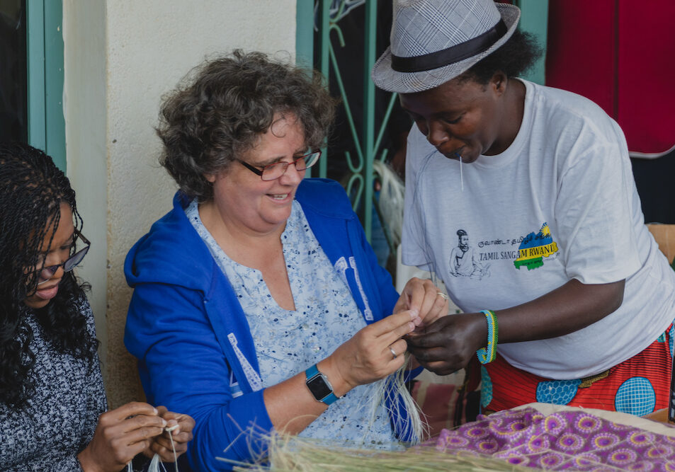 Jeanne, Talking through Art beneficiary, helps Marlies, a member of the Africa International Club of Rwanda, to get started with weaving. TTA HQ in Rwanda.