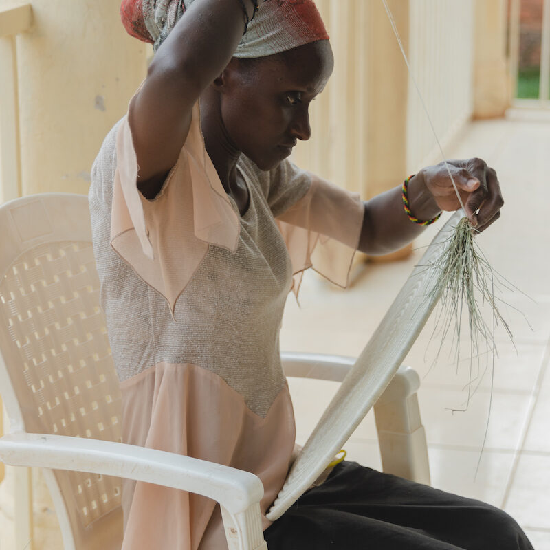 Emilienne Muhawenimana (beneficiary) weaving at Talking through Art headquarters in Kigali. Emilienne has been a TTA member for 4 years, after a neighbour let her know about the organization. Prior to TTA, she would be at home not doing much, and she didn't see much of a future for herself. Now she is a dedicated weaver, and also does most of the cooking at TTA. Emilienne lives on site.